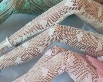 May include: Three pairs of white lace tights with different patterns. The tights are on a white surface.