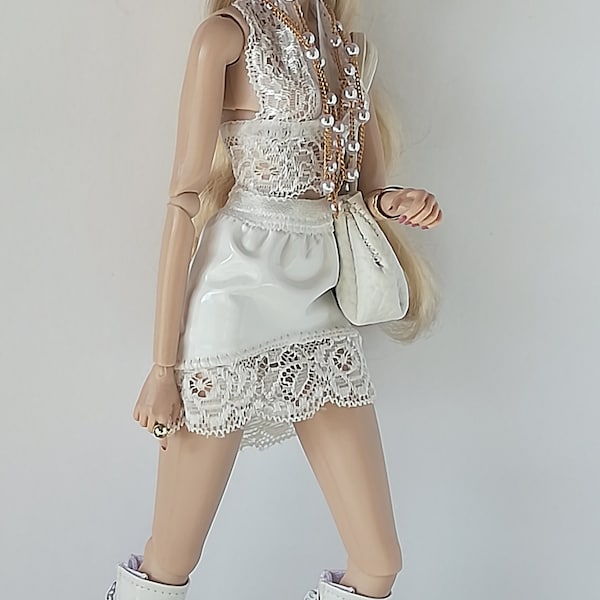 May include: A fashion doll in a white outfit, including a halter top, skirt, and knee-high boots. The doll wears black sunglasses, gold jewelry, and carries a white purse. The boots have cut-out details.