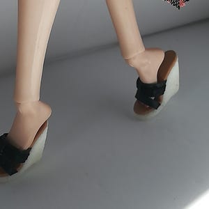 Op de afbeelding: Een paar zwarte wedgesandalen met een wit platform. De sandalen hebben meerdere banden over de voet en enkel.