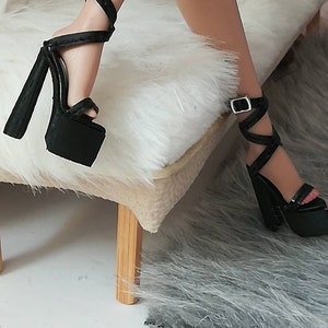 May include: A pair of black platform sandals with ankle straps and buckles. The sandals have a thick platform and a high heel.