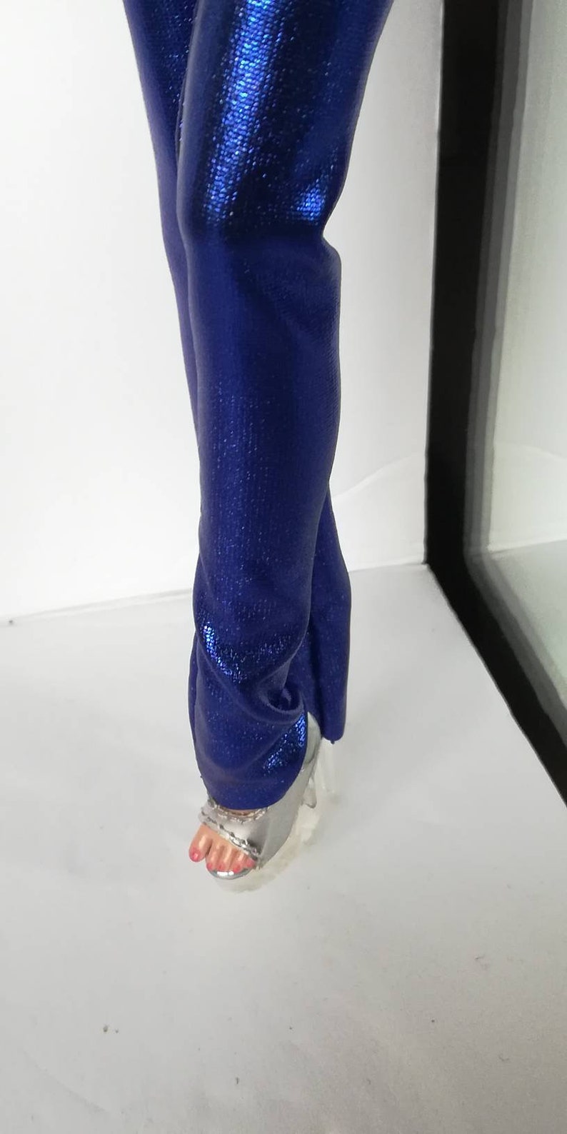 May include: A pair of blue metallic trousers with a silver platform sandal.