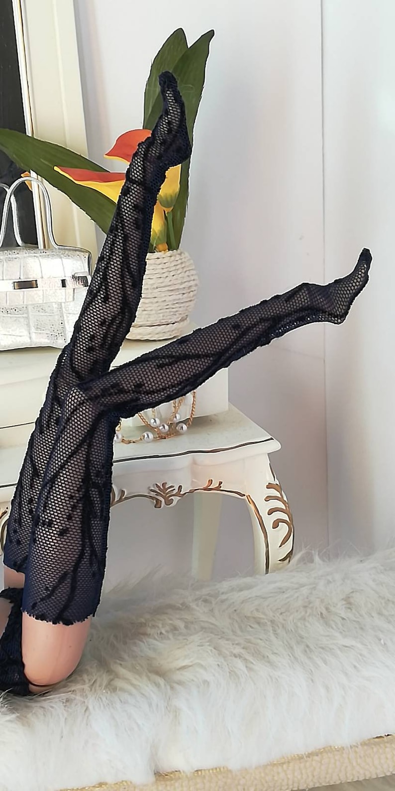 May include: Black fishnet stockings with a delicate floral pattern. The stockings are worn on a pair of legs and are shown against a white background.