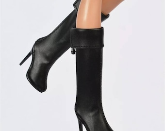 May include: A pair of black knee-high boots with a stiletto heel. The boots have a fold-over top and a pointed toe.