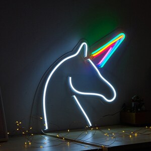 May include: A white neon unicorn head with a rainbow horn. The unicorn is lit up and the horn is a vibrant rainbow of colors.