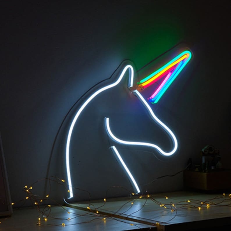 May include: A white neon unicorn head with a rainbow horn. The unicorn is lit up and the horn is a vibrant rainbow of colors.