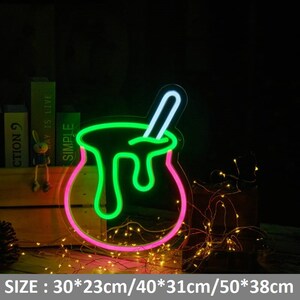 May include: Neon sign shaped like a pot with a green liquid and a white stick inside. The pot is outlined in pink. The sign is 30 inches by 23 inches, 40 inches by 31 inches, or 50 inches by 38 inches.