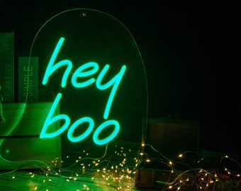 May include: A neon green sign with the words "hey boo" in a script font. The sign is on a clear, arched background. The image includes string lights and the text "SIZE : 30*35cm/40*46cm/50*58cm".