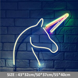May include: A white neon unicorn head with a rainbow horn on a brick wall. The sign reads "SIZE: 43*32cm/50*37cm/55*40cm".