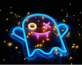 May include: Blue neon ghost sign with a pink smiling face and crossed eyes. The sign is 30 by 28 centimeters or 40 by 37 centimeters.