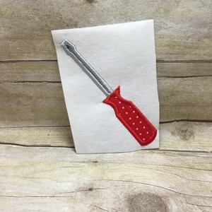May include: A red and silver screwdriver with white polka dots on the handle. The screwdriver is on a white background.
