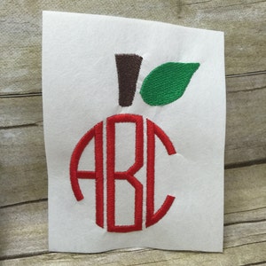 May include: Red embroidered apple with a green leaf and a brown stem. The apple has the letters "ABC" in a circle inside.