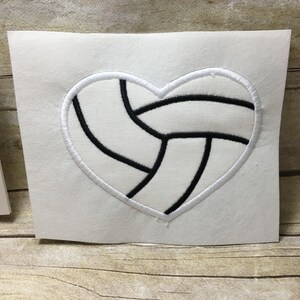 May include: White heart-shaped patch with a black embroidered volleyball design.