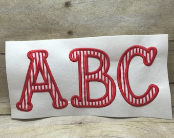 Puede incluir: Letras de tela a rayas rojas y blancas que deletrean "ABC".