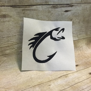 May include: Black and white embroidered design of a fish hook with a fish's head on the hook. The design is on a white fabric.