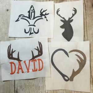 May include: Four embroidered patches with hunting and fishing themes. The patches feature a fish and duck with a fleur-de-lis, a deer head, a heart with antlers, and antlers with the name "DAVID" embroidered in orange.