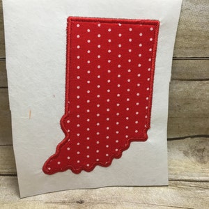 May include: Red fabric applique of the state of Indiana with white polka dots. The applique is on a white background.