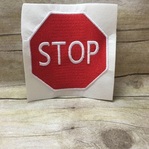May include: A red octagonal stop sign with white lettering. The sign says "STOP" in all capital letters.