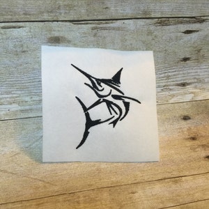 May include: A white square patch with a black marlin fish design. The marlin is illustrated in a minimalist style, with a long, pointed bill and a prominent dorsal fin. The patch is designed for application to fabric, possibly by sewing or ironing.