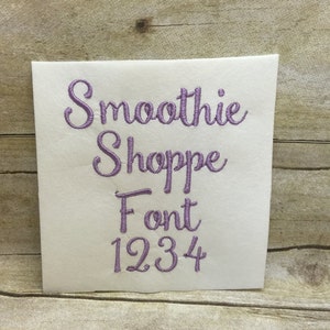 May include: A white card with the text "Smoothie Shoppe Font 1234" in purple embroidery.