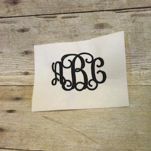 May include: A black embroidered monogram with the letters "ABC" in a cursive font.