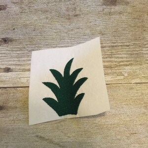 Op de afbeelding: Een geborduurde patch met een gestileerde plant met vijf bladeren, in groen.