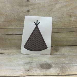 Puede incluir: Un parche bordado de color marrón y negro que representa una tienda de campaña tipi con un patrón de chevron.