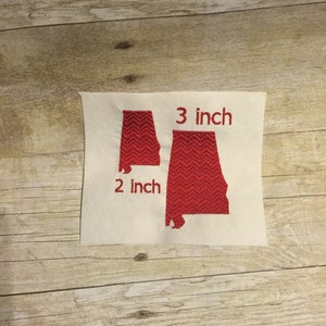 May include: Two red embroidered outlines of the state of Alabama, one measuring 2 inches and the other 3 inches.