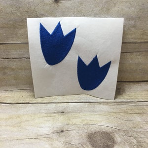 May include: Two blue dinosaur footprints on a white background.