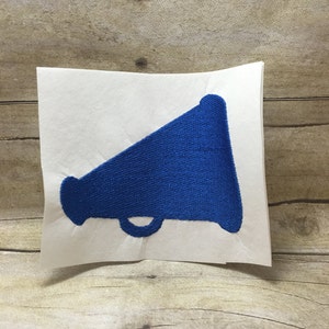 May include: A blue embroidered megaphone design on a white background.