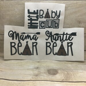 May include: Three white iron-on patches with black embroidery. The top patch says "Baby Cub" with a small tent graphic. The bottom two patches say "Mama Bear" and "Auntie Bear" with a small tent graphic on each.