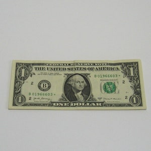May include: A one dollar bill with a portrait of George Washington. The bill is green and has the words "Federal Reserve Note" and "The United States of America" printed on it. The serial number is B01966603.
