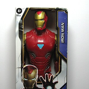 May include: A red and gold Iron Man action figure in its original packaging. The figure has a detailed design, with a red body, gold accents, and a blue chest emblem. The packaging features the words "Iron Man" and the age range "4+".