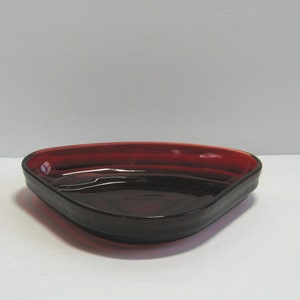 May include: A triangular red glass dish with a slightly curved rim.