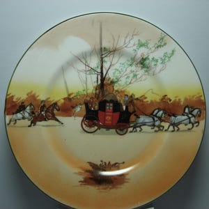 May include: A decorative plate featuring a historical scene with a horse-drawn carriage and riders on horseback. The plate has a cream-colored background with a green rim and a detailed illustration in shades of red, black, and brown.