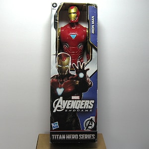 May include: Iron Man action figure in a box. The figure is red and gold, with a detailed design. The box features the Marvel Avengers Endgame logo and the words "Titan Hero Series". The figure is approximately 12 inches tall.