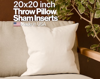 May include: A white 20x20 inch throw pillow sham insert, made in the USA. The insert is sitting on a beige couch with a wooden armrest. A green plant is in the background.