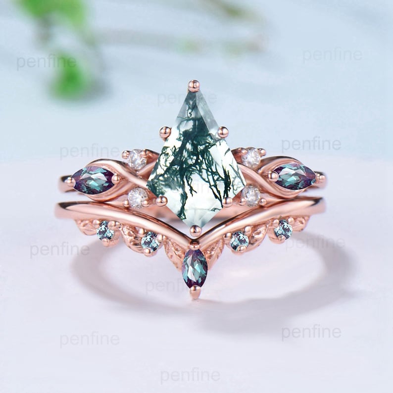May include: A rose gold engagement ring with a moss agate center stone and a matching band. The moss agate is a light green with dark green veins. The band is set with smaller clear stones and amethyst stones.