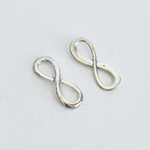 May include: Two silver infinity symbol charms. The charms are smooth and shiny.