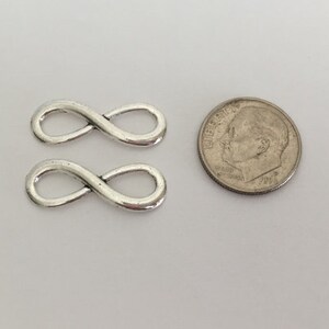 May include: Two silver infinity symbol charms, each about the size of a US dime.