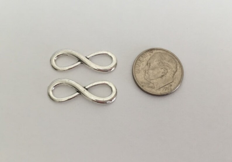 May include: Two silver infinity symbol charms, each about the size of a US dime.
