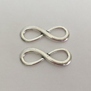 May include: Two silver infinity symbol charms. The charms are smooth and shiny.