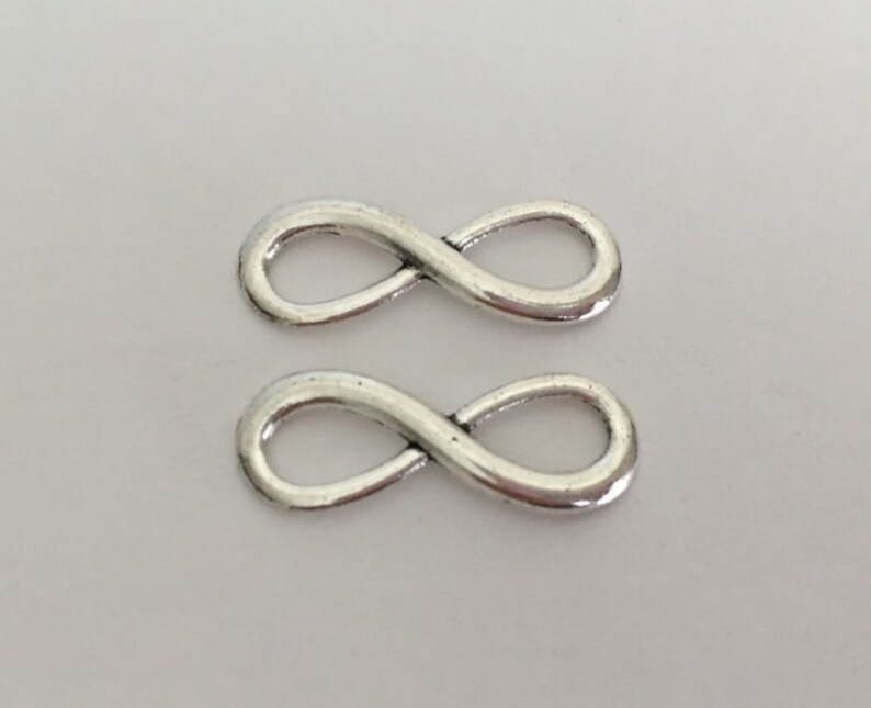 May include: Two silver infinity symbol charms. The charms are smooth and shiny.