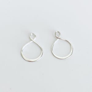 May include: Two silver-colored, open-loop earrings. Each earring has a teardrop shape with a looped top. The earrings are displayed on a white background. The earrings are likely made of sterling silver.