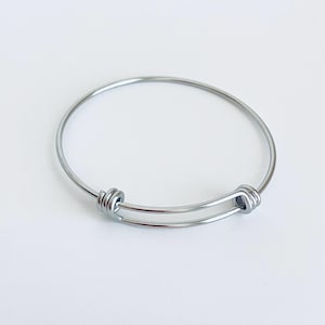 May include: A silver expandable bangle bracelet with a simple design.