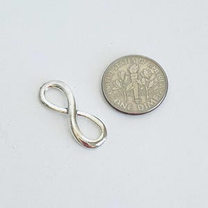 May include: A silver infinity charm pendant, approximately the size of a US dime.