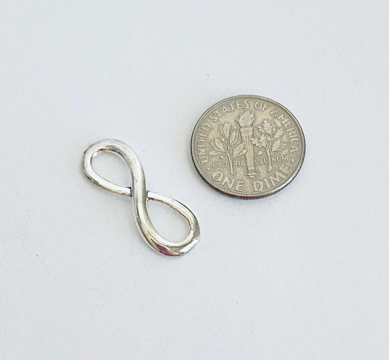 May include: A silver infinity charm pendant, approximately the size of a US dime.
