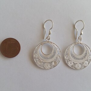 Puede incluir: Un par de pendientes de filigrana de plata con un dise&ntilde;o circular. Los pendientes son aproximadamente del tama&ntilde;o de una moneda de 1 euro.
