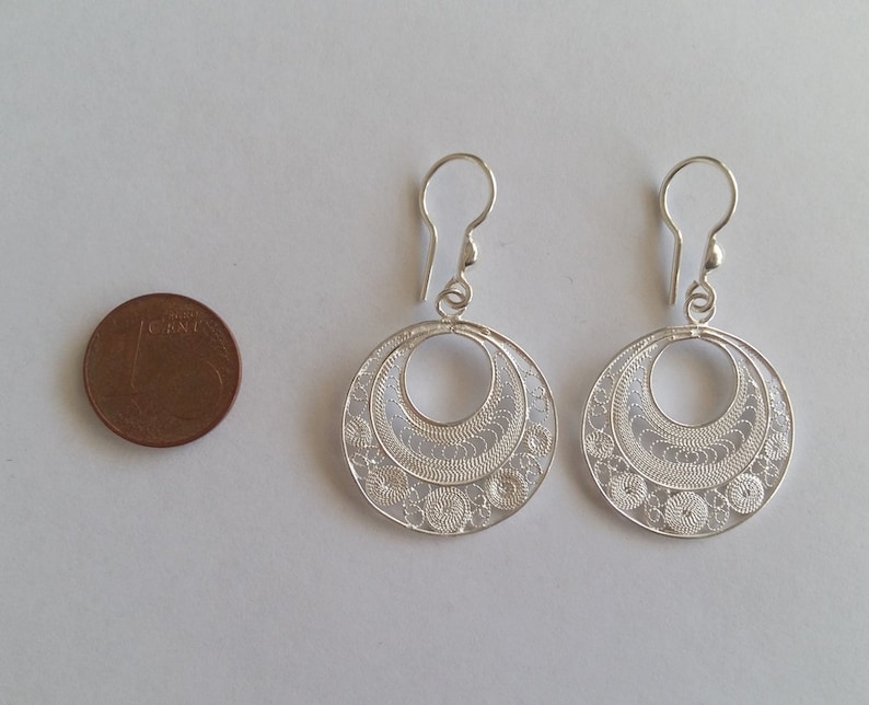 Puede incluir: Un par de pendientes de filigrana de plata con un dise&ntilde;o circular. Los pendientes son aproximadamente del tama&ntilde;o de una moneda de 1 euro.