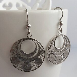 Puede incluir: Un par de pendientes de filigrana de plata con un dise&ntilde;o circular. Los pendientes est&aacute;n hechos de un delicado e intrincado trabajo de alambre y tienen una forma de gota colgante.
