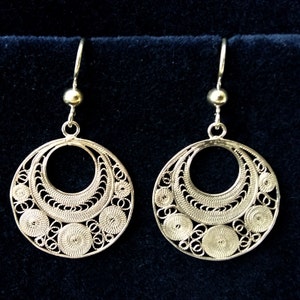 Puede incluir: Un par de pendientes de filigrana de plata con un dise&ntilde;o circular. Los pendientes tienen un patr&oacute;n delicado e intrincado y son perfectos para agregar un toque de elegancia a cualquier atuendo.